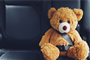 A teddy bear sitting in the back seat of a car, looking cozy and ready for a fun ride.